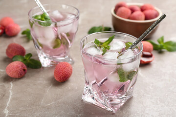 Lychee cocktail with mint and ice on grey table, space for text