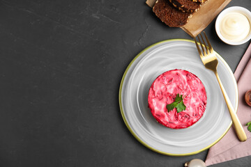 Herring under fur coat served on black table, flat lay with space for text. Traditional russian salad