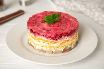 Herring under fur coat served on white table, closeup. Traditional russian salad