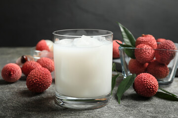 Glass with lychee juice and fresh fruits on grey table