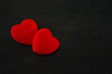 Fototapeta premium two red hearts on a black wooden background. Valentines Day concept. The 14th of February.