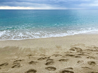 Seashore in Alanya, Turkey. Cleopatra beach. Calm sea and lowering cloudy sky. Many steps on the sand.