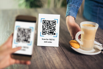 Women's hands are using the phone to scan the qr code to select menu. Scan to get discounts or pay...