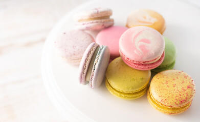 Multi-colored macarons close up on wood background with soft lights. Delicate French dessert for breakfast in the morning light