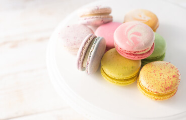 Multi-colored macarons close up on wood background with soft lights. Delicate French dessert for breakfast in the morning light