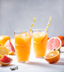 Citrus juice in two glasses and fresh fruit tangerine, orange, grapefruit and lemon on a gray background