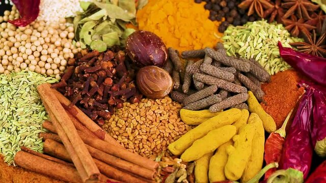 Various spices, peppers and herbs close-up top view in a circular rotation. Eastern spice market.