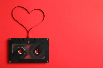 Top view of music cassette and heart made with tape on red background, space for text. Listening love song