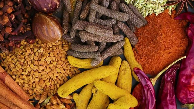 Various spices, peppers and herbs close-up top view in a circular rotation. Eastern spice market.