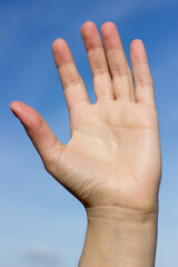Single hand against blue sky