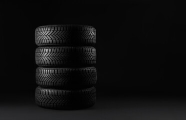 Fototapeta na wymiar Winter tires on black background. Space for text