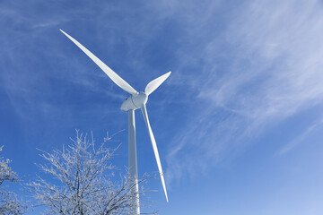wind turbine on sky. Large wind turbine next to a tree with snow. Wind turbine in winter. Winter in...