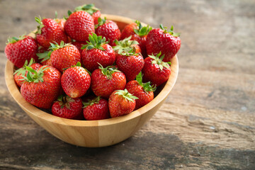 wooden bowl strawberry on textured wooden table. 
