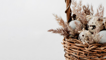 Easter composition with small eggs and dry. fluffy grass in wicker basket. Happy easter celebration, easter hunt