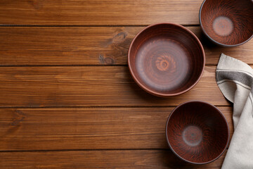 Clay bowls on wooden table, flat lay with space for text. Handmade utensils