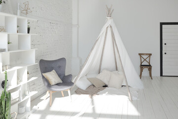 Fototapeta na wymiar Spacious stylish modern trendy loft apartment in white and light colors. brick wall, wood floor, shelving, pallet bed and teepee-shaped children's house. everything is white with gray tints.