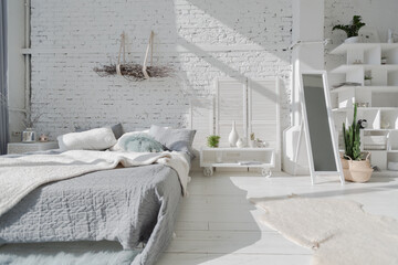 Spacious stylish modern trendy loft apartment in white and light colors. brick wall, wood floor, shelving, pallet bed and teepee-shaped children's house. everything is white with gray tints.
