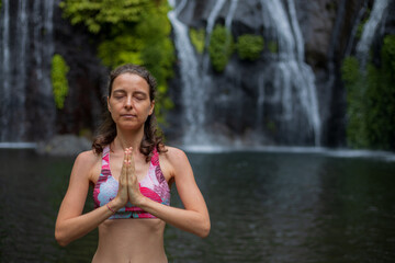 Obraz premium Close up of namaste mudra. Young woman meditating, practicing yoga and pranayama with namaste mudra near waterfall. Yoga outdoor concept. Copy space. Banyumala waterfall Wanagiri, Bali.