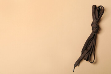 Brown shoelaces on beige background, top view. Space for text