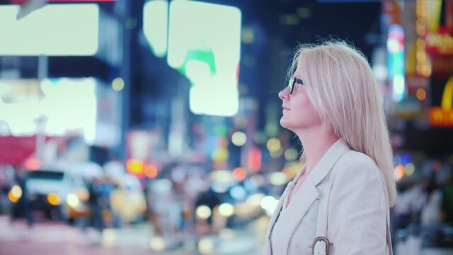 Business woman admires the bright lights of the famous Times Square in New York