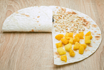 a quick snack of tacos with bananas, mangoes, peanuts and chocolate spread. Junior cooking  - step 2, fold the filling inside