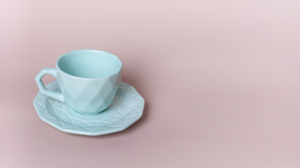 Empty light blue cup and saucer on a powder pink background. Stylish crockery. Selective focus.