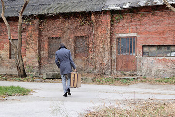 Rear view of a man with suitcase walking away.