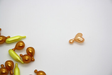 Gold and pink capsules with cosmetic oil for the face.