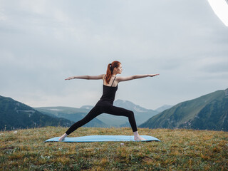 Woman practices yoga on a rug outdoors in the mountains fresh air tourism