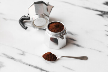 A traditional Italian espresso maker - Moka pot, a spoon with coffee on a marble table