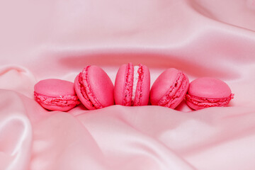 French pink macaroon cookies on silk tablecloth.