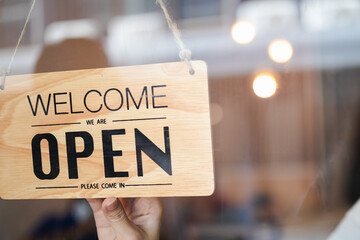 Hand of woman owner retail,coffee shop woman turning sign board to open with wearing face mask...