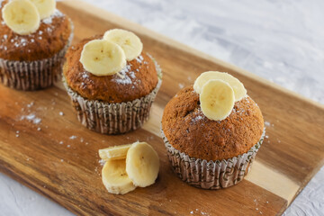 Three homemade banana muffins as illustration of easy recipe or food menu on wooden background