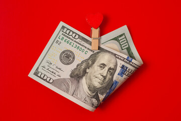 100 with a gift in the form clothespin of a red heart on red table. Valentine's day concept background