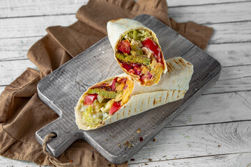 A delicious doner donair kebab wrap with falafel, lettuce, tomato,  onion and sauce.