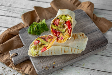 A delicious doner donair kebab wrap with falafel, lettuce, tomato,  onion and sauce.