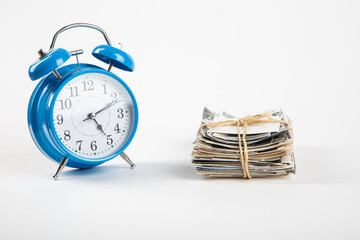 A stack of old photos with an alarm clock on a white background.Photography and time.