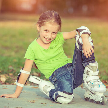 Little girl on roller skates sitting in park