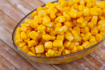 Cooked sweet corn kernels in bowl on wooden table