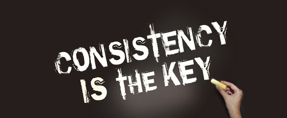 Consistency is the Key chalkboard with text and hand holding piece of cahlk. Business success concept - obrazy, fototapety, plakaty