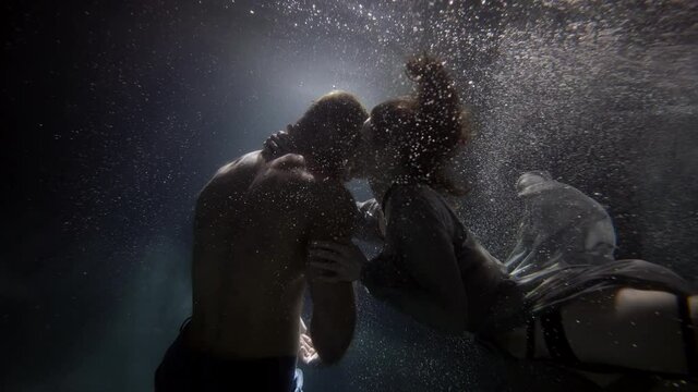 young woman is flirting with handsome man underwater, lovers in swimming pool, magic love story