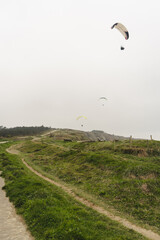 Paragliding over the green cliffs on an overcast day