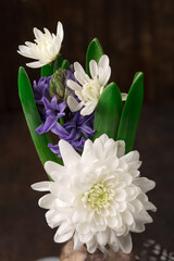 Easter Decoration with gray golden eggs, quail feathers, hyacinth daisy flowers on dark wooden background. Happy Easter card concept.