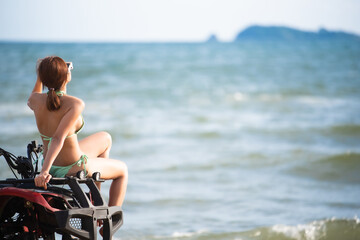 Asian young beautiful woman model in a bikini pose with ATV bike at the beach.summer vacation.