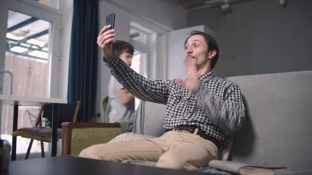 Guy waves his hand on the video on his phone