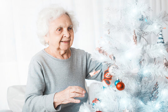 Smiling senior woman decorating fancy christmas tree