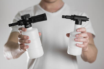 A man holds a foam generator for a high pressure washer. Close up. Isolated on a gray background