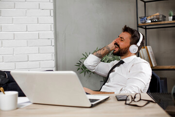 Attractive businessman in office. Young businessman with headphones singing at work.