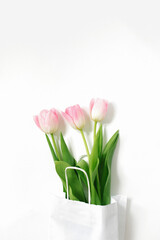 Flat lay composition with pink tulips in paper bag on beige background. Greeting card for Valentine's Day, Mother's Day, Birthday. The concept of spring