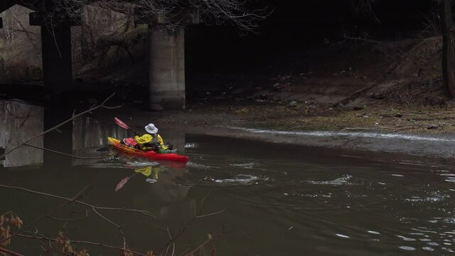man kayaking river winter under the bridge